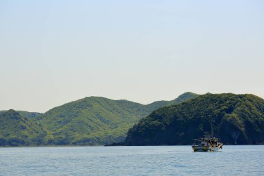 Denizdeki kayık Yeşil dağların önünde 