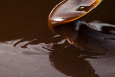Siyah arka plana çikolata şurubu döküyorum. seçici odak.