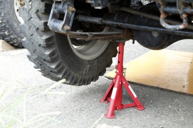 Beton yüzeyde araç lastiği destekleyen kırmızı kriko.