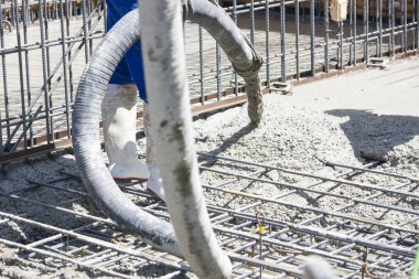 İnşaat alanında inşaat işçisi, beton temeller döküyor.