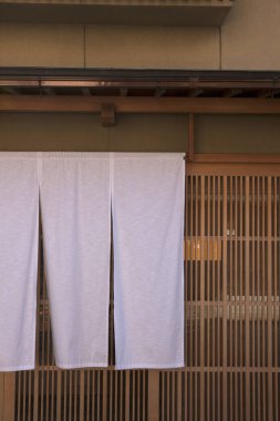 Geleneksel ahşap binanın girişinde asılı beyaz kumaş perde