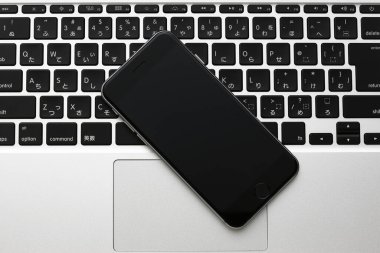 Siyah akıllı telefon ve dizüstü bilgisayar beyaz masada. düz yat