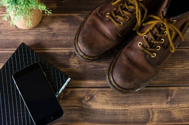 Ahşap masa üzerinde deri çizmeleri olan modern ofis ekipmanlarının en üst görüntüsü.