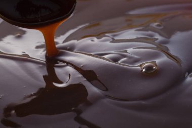 Kepçeden akan koyu siyah sos.