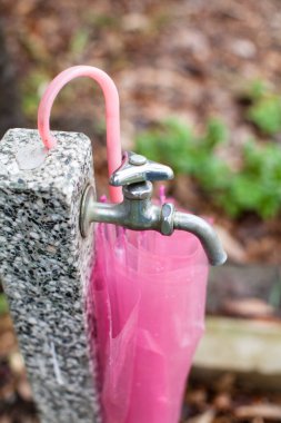 Bahçede pembe şemsiyeli musluk