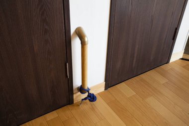 İki ahşap kapının yanındaki duvara bağlanmış metal boru.