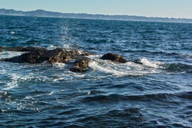 Kayalıklarda dalgalar olan güzel bir deniz manzarası. Doğa