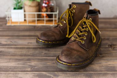 Kahverengi deri çizmeler ve tahta arka planda ayakkabılar