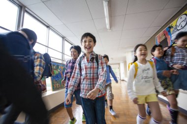 Okulda koşan bir grup mutlu Asyalı öğrenci.