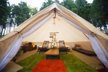 İçinde yatak ve sandalyeler olan büyük beyaz bir çadır. 