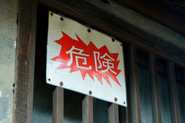 Dışarıdaki ahşap parmaklıkların üzerine Japon tehlike uyarısı asılmış.