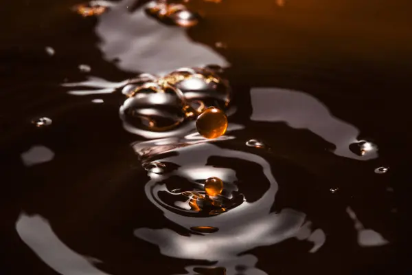 macro photo of circles on the dark water, pouring black liquid