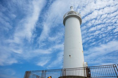 Deniz feneri gururla yükselir parlak mavi gökyüzüne.