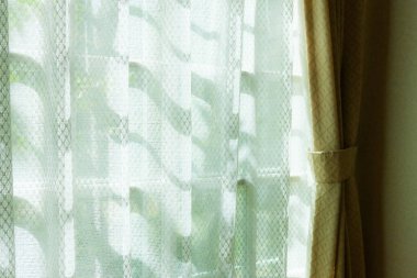 Penceresinde perdeler olan rahat bir oda. 