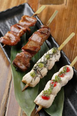 Yaprak kaplı siyah tabakta ızgara şişler