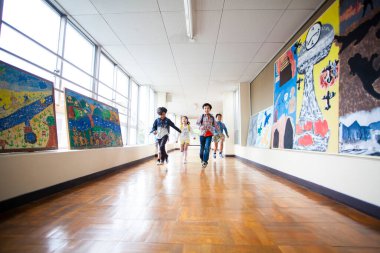 Okulda koşan bir grup mutlu Asyalı küçük öğrenci.