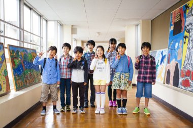 Asyalı bir grup mutlu öğrenci ayakta ve poz veriyor.