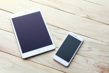 Modern tablet bilgisayar ve ahşap masadaki akıllı telefon.