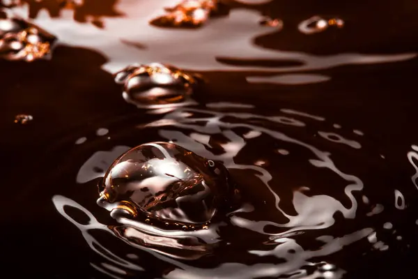 macro photo of circles on the dark water, pouring black liquid