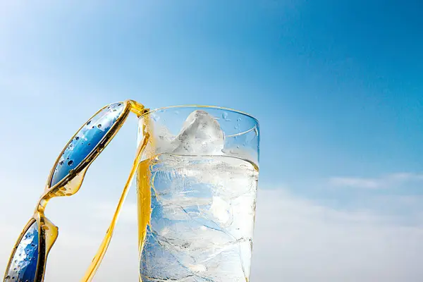 Glas Water Met Ijsblokjes Gele Zonnebril Achtergrond Van Blauwe Lucht — Stockfoto