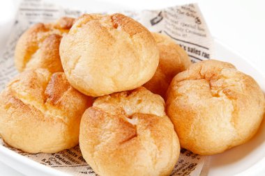 Gazetedeki taze çörekler beyaz kasede, yakın plan.