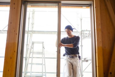 Ahşap bina inşaatında çalışan Asyalı genç bir inşaatçının portresi.