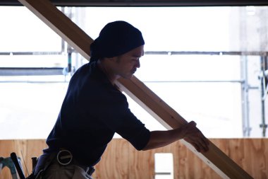 Ahşap bina inşaatında çalışan genç Asyalı marangozun portresi.