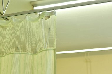 Perdelerin yakın görüntüsü, hastane odasındaki tıbbi ekipmanlar.       