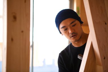 Ahşap bina inşaatında çalışan Asyalı genç bir inşaatçının portresi.