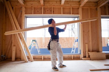 Ahşap bina inşaatında çalışan genç Asyalı marangozun portresi.