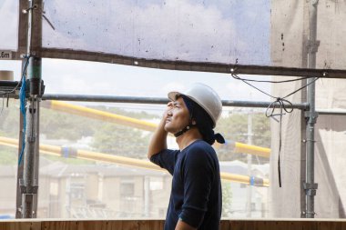 Asyalı genç inşaatçının ve şantiyenin portresi