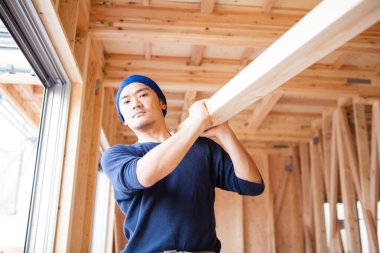 Ahşap bina inşaatında çalışan genç Asyalı marangozun portresi.