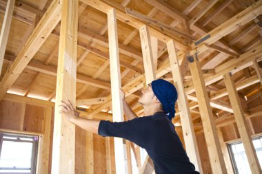 Ahşap bina inşaatında çalışan genç Asyalı marangozun portresi.