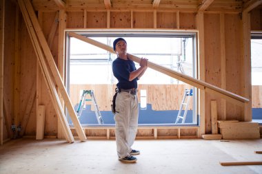 Ahşap bina inşaatında çalışan genç Asyalı marangozun portresi.