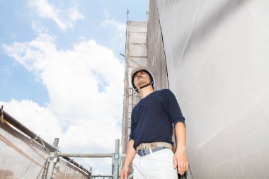 Ahşap bina inşaatında çalışan genç Asyalı marangozun portresi.