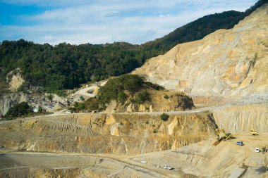 Büyük açık maden ocağı kayalık tepelerin arasında.