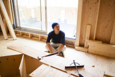 Ahşap bina inşaatında çalışan Asyalı genç bir inşaatçının portresi.