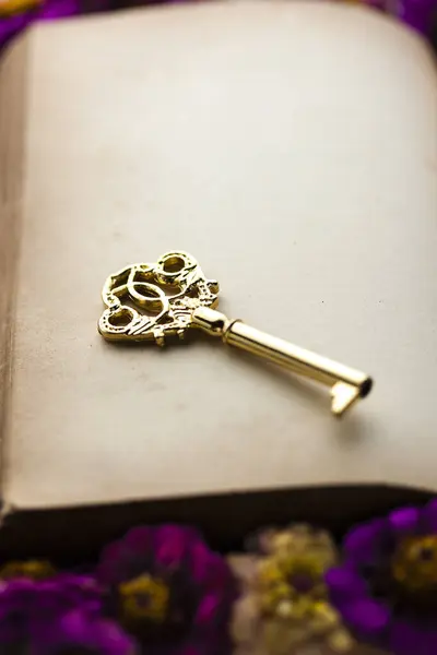 golden key on a book with flowers