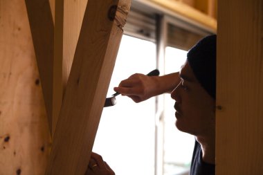 Ahşap bina inşaatında çalışan Asyalı genç bir inşaatçının portresi.