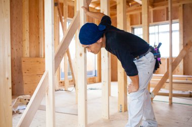 Ahşap bina inşaatında çalışan genç Asyalı marangozun portresi.