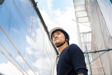 Asyalı genç inşaatçının ve şantiyenin portresi