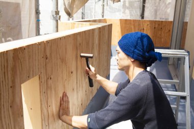 Ahşap bina inşaatında çalışan Asyalı genç bir inşaatçının portresi.