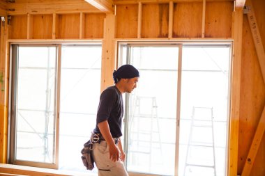 Ahşap bina inşaatında çalışan Asyalı genç bir inşaatçının portresi.