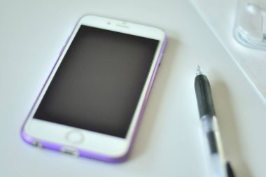 Beyaz arkaplanda izole edilmiş kalem ve cep telefonlu defter