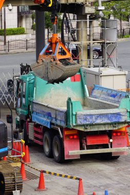Kentteki inşaat alanında çalışan kamyon ve vinç.