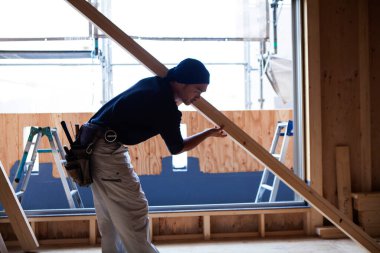 Ahşap bina inşaatında çalışan genç Asyalı marangozun portresi.