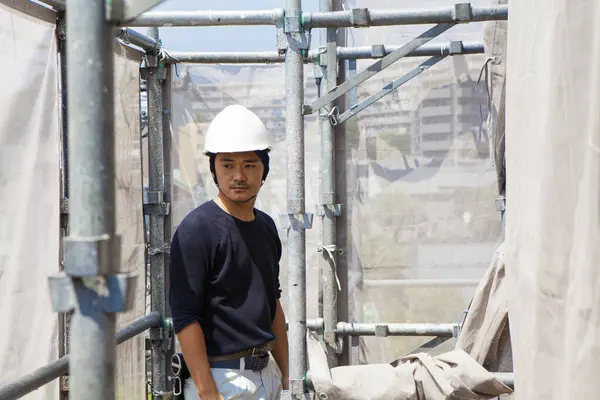portrait of handsome japanese worker posing on the construction site