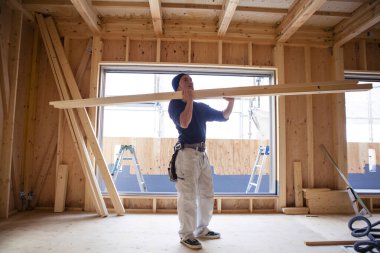 Ahşap bina inşaatında çalışan genç Asyalı marangozun portresi.