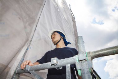 Asyalı genç inşaatçının ve şantiyenin portresi