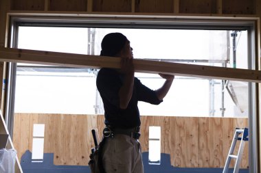 Ahşap bina inşaatında çalışan genç Asyalı marangozun portresi.